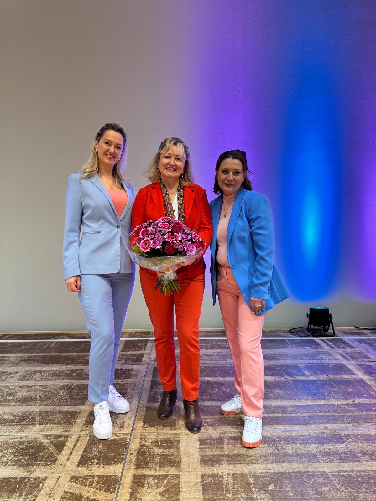Hanna Czarnecka mit zwei Kolleginnen und Blumenstrauß auf der Bühne der Kinder-Eventwelt